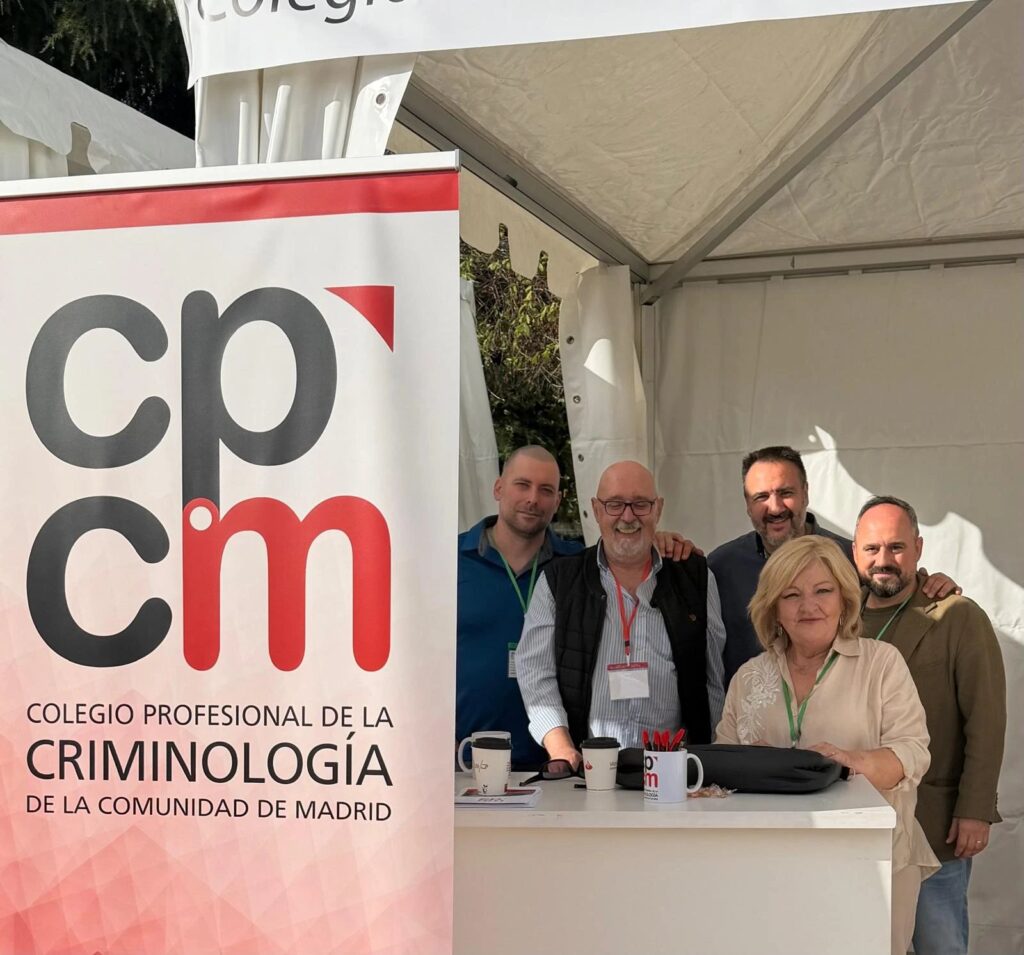 Cinco representantes del Colegio Profesional de la Criminología de la Comunidad de Madrid sonríen en la carpa del Colegio, junto al cartel enrollable del CPCM, en el Día de las Profesiones 2026.