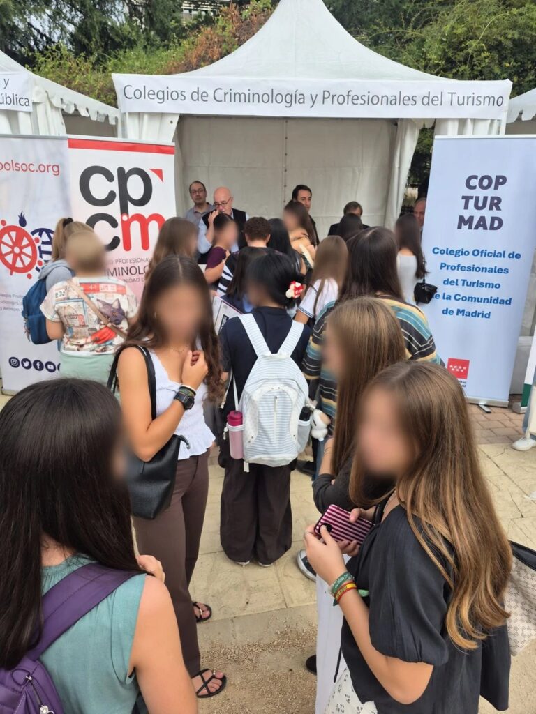 Estudiantes agolpados ante la carpa del Colegio, junto al cartel del CPCM y al del Colegio Oficial de Profesionales del Turismo de la Comunidad de Madrid.