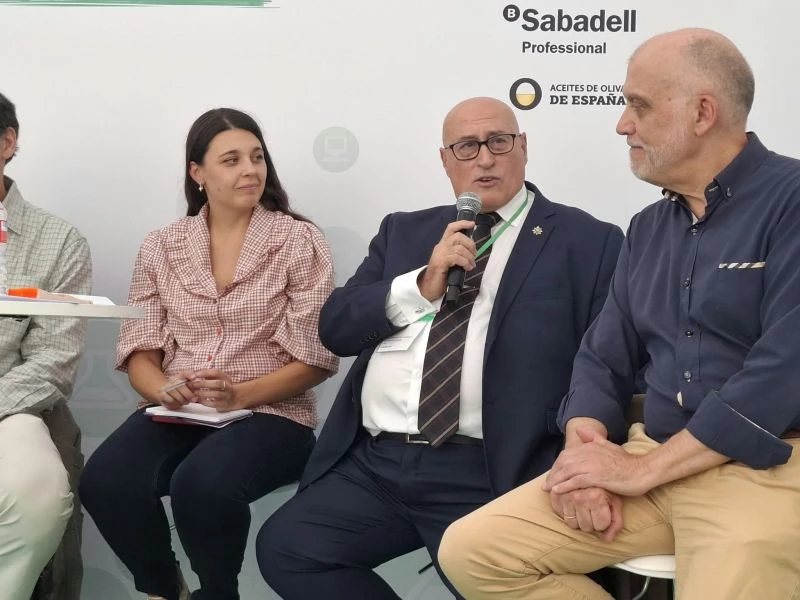 Participantes en una mesa redonda del Día de las Profesiones 2026, sentados ante un panel con los logotipos de Sabadell Professional y Aceites de Oliva de España; uno de ellos habla al micrófono.
